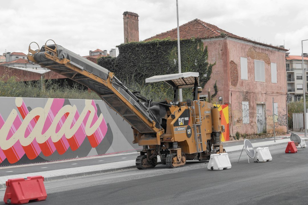 A yellow road milling machine on a newly paved street